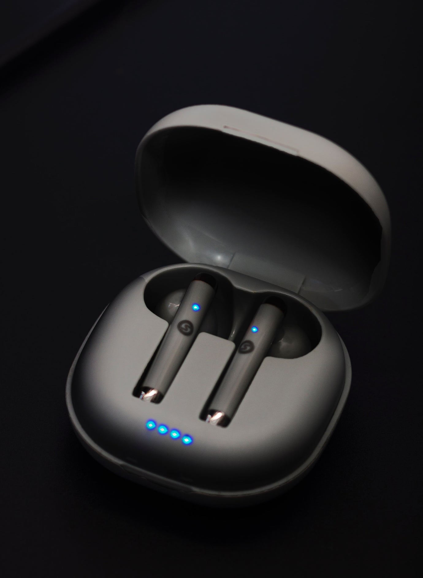 Black earbuds in an open case with blue lights