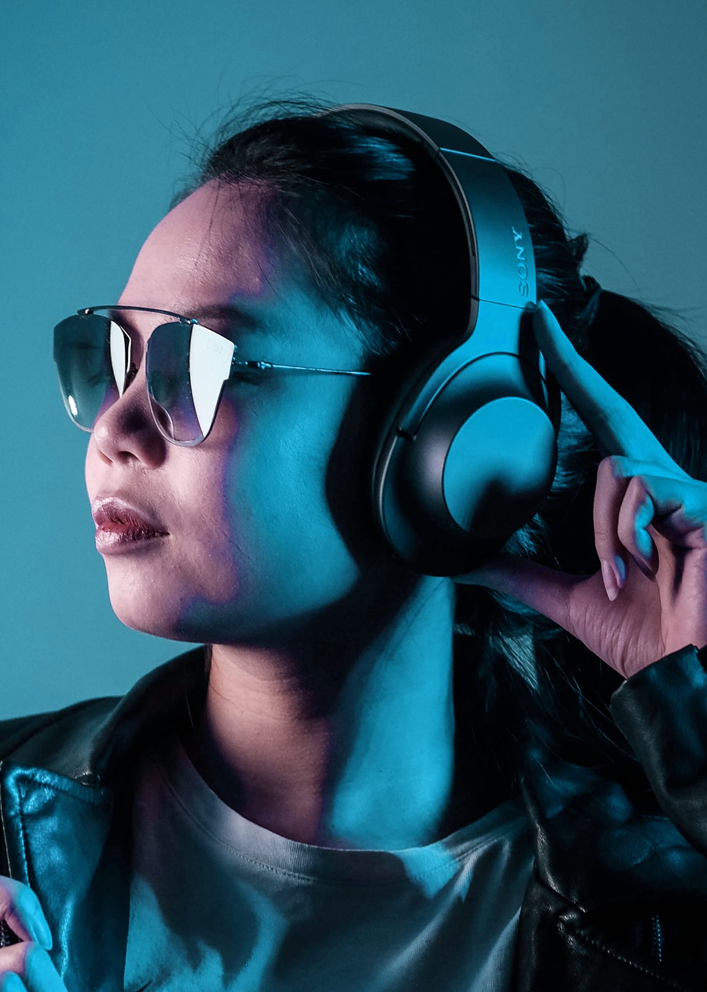 Asian woman with sunglasses holding headphones on her head
