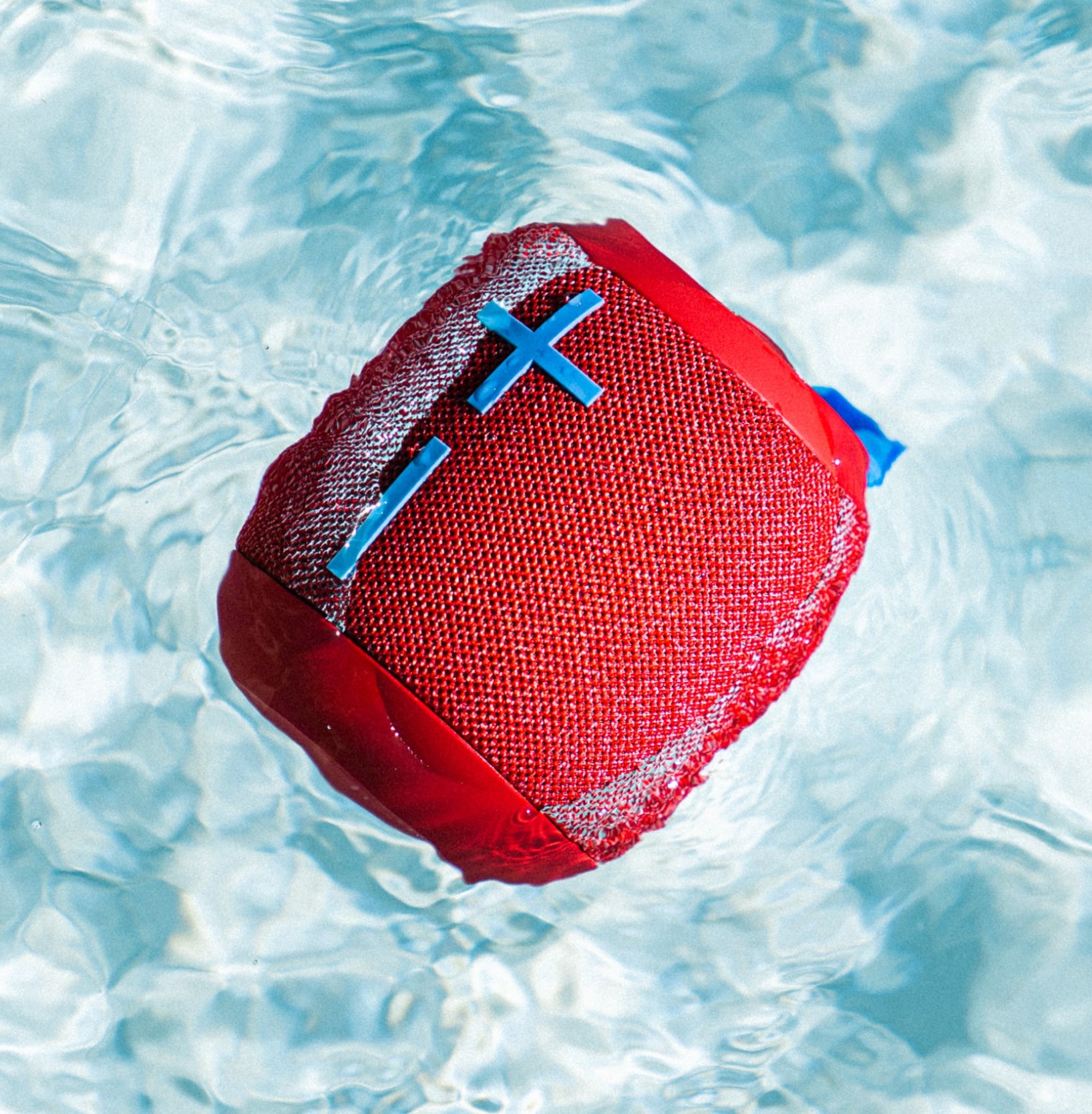 A red wireless speaker floating in the water